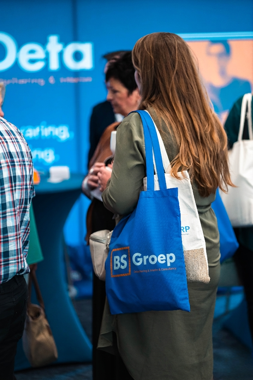 Bezoeker met BS Groep tas op een beurs